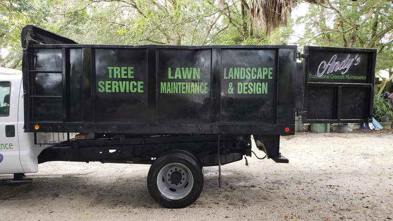Andy's PGM dump truck with a black box lettered Tree Service, Lawn Maintenance, and Landscape & Design.